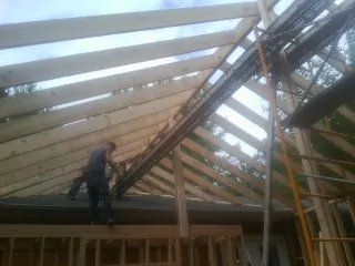 Rafters going up over a new addition with a worker on the wall in Whiteville