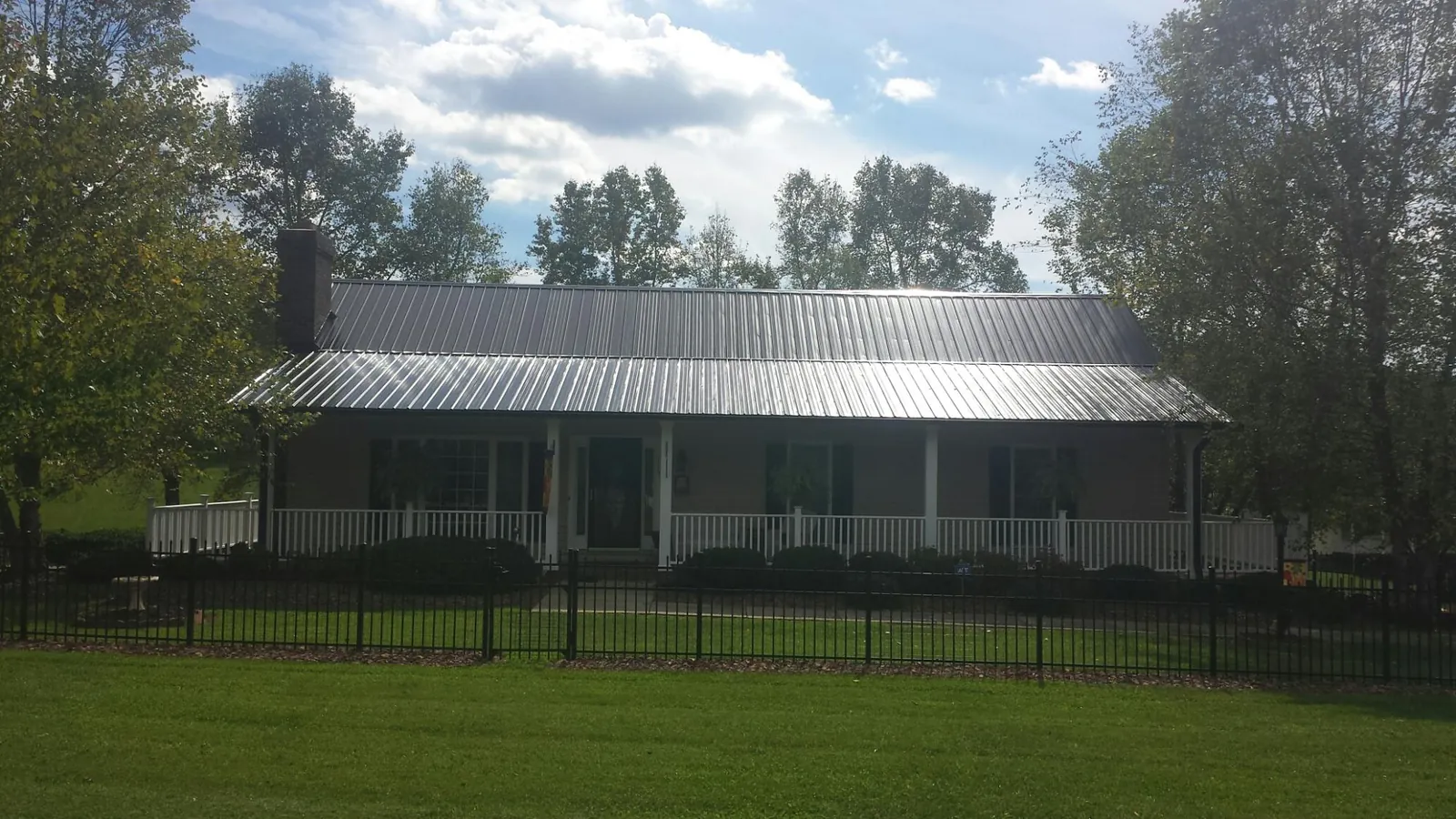 Gray metal roof on a brick ranch with a full width front porch — Gutter Guard Installation work by our crew in Whiteville